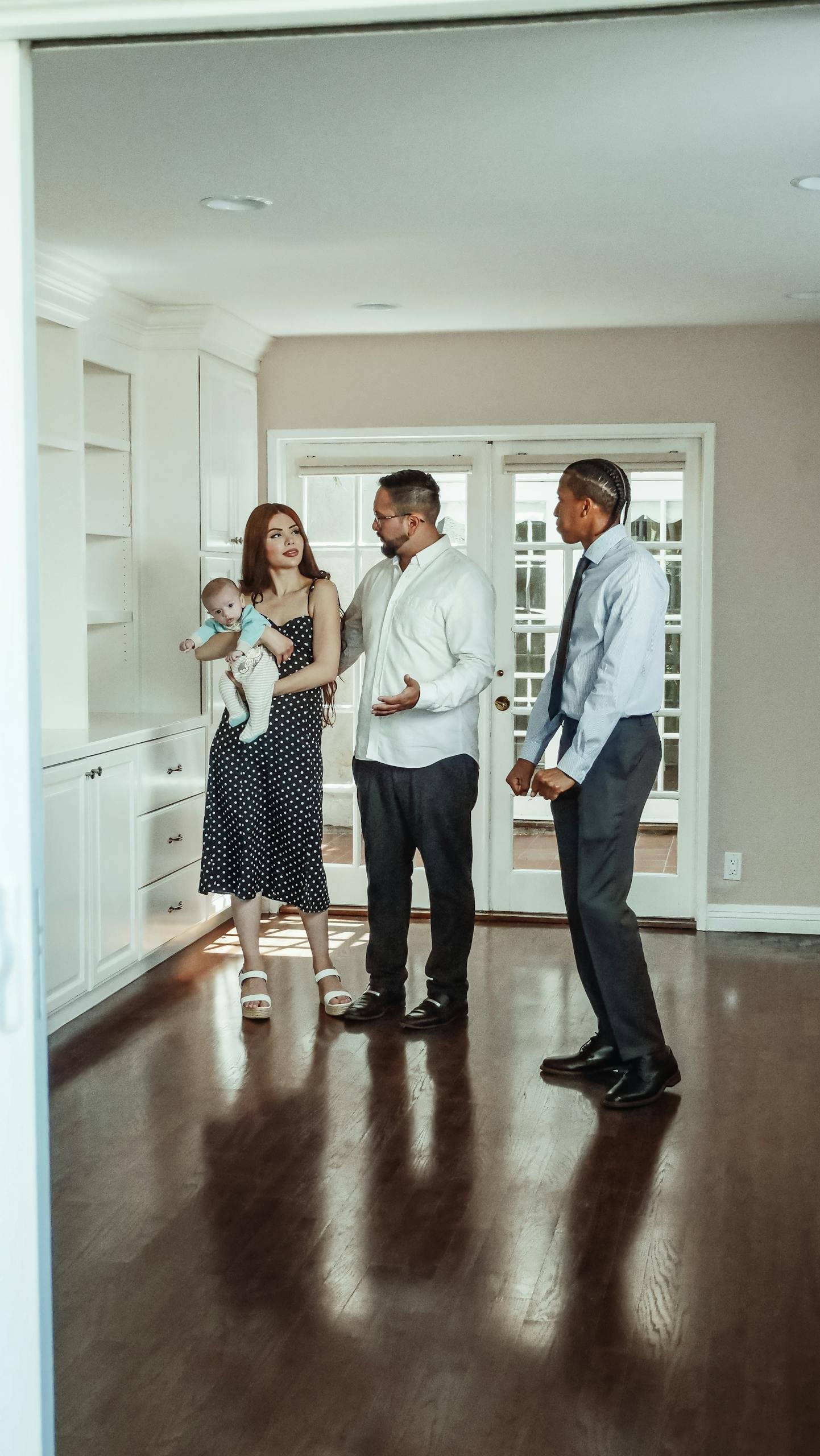 A couple with a baby and a realtor discuss details during a home tour.